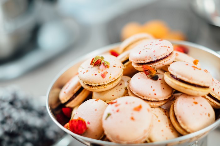 Pink macarons with rose bud garnish in a bowl