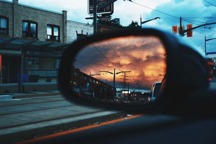Sunset reflected in a car mirror on a city street