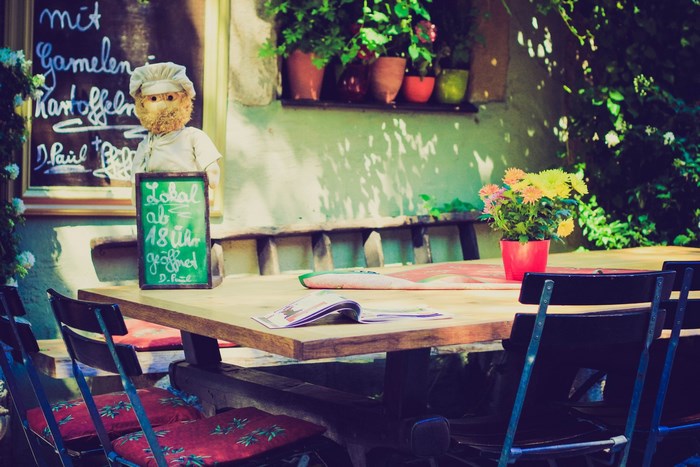 Teddy bear chef with menu outside a cafe