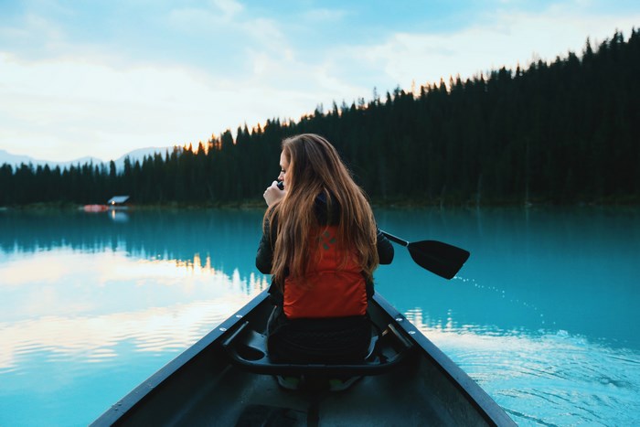Woman Paddling Canoe on Serene Blue Lake at Dawn