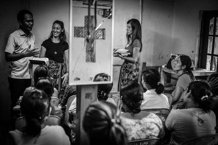 People gathered in a room for a presentation with a cross