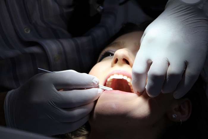 Dentist examining a woman's teeth with instruments