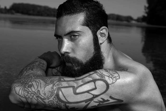Man with beard and tattoos in black and white