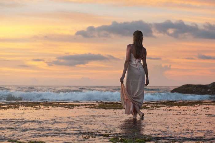 Woman walking on beach at sunset