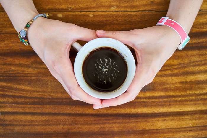 Hands holding a cup of coffee on a wooden table