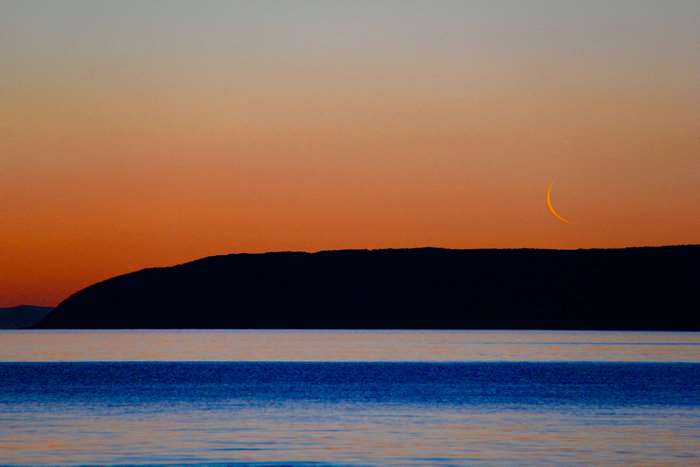 Crescent Moon over Ocean and Island at Sunset
