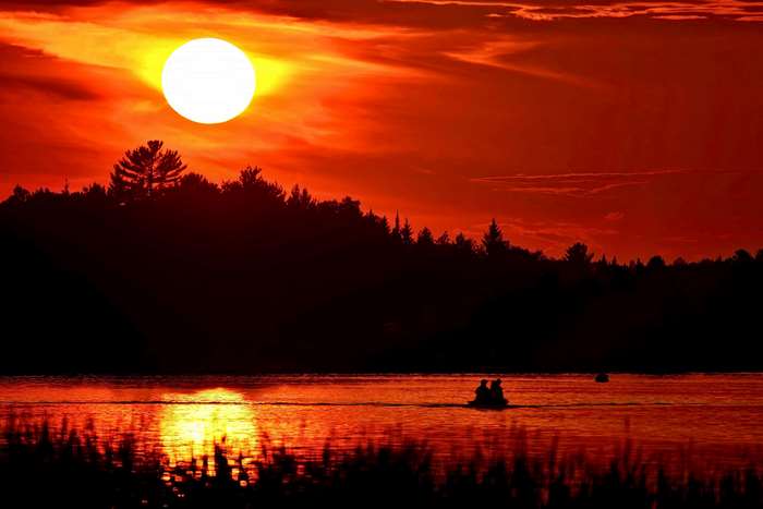 Sunset over lake with people in a boat