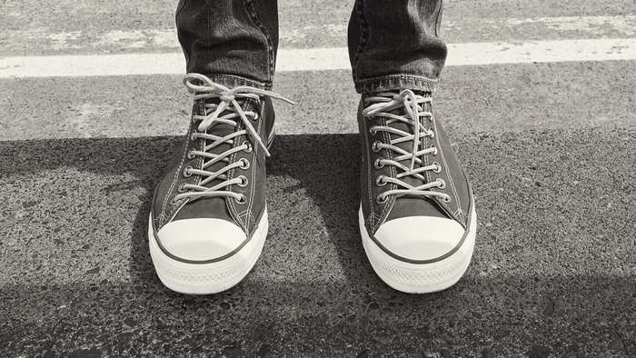 Person wearing black Converse sneakers on a street