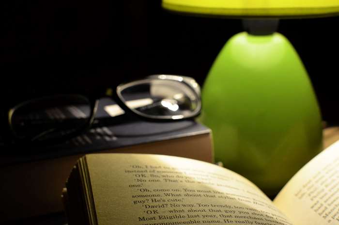 Book and glasses next to a lamp