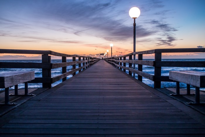 Wooden pier with lamps at sunset over the sea