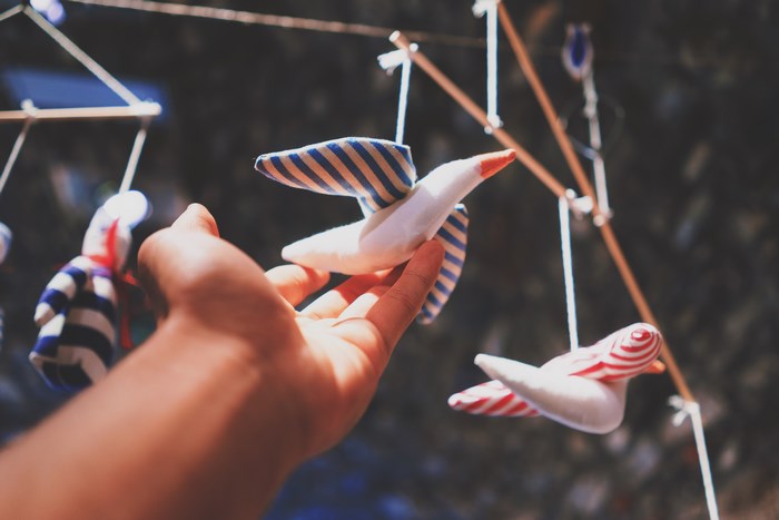 Hand reaching for a handmade bird mobile