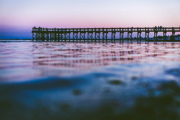 Wooden pier over water at dusk with purple sky