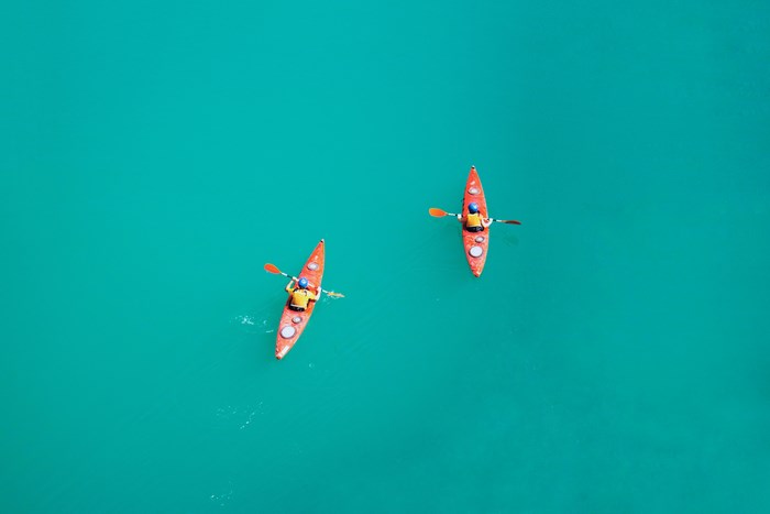 Two people kayaking on a turquoise lake from above