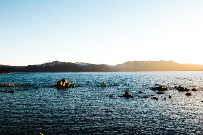 Lake with mountains and rocks at sunset