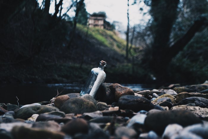 Message in a bottle on a rocky riverbank