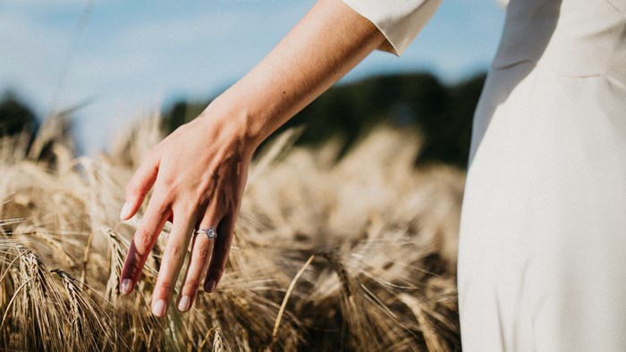 Woman's hand with engagement ring in wheat field