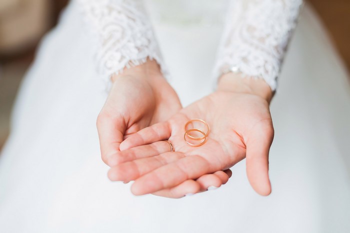 Bride Holding Wedding Bands with Lace Sleeves