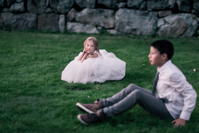 Girl in a white dress and boy sitting on grass