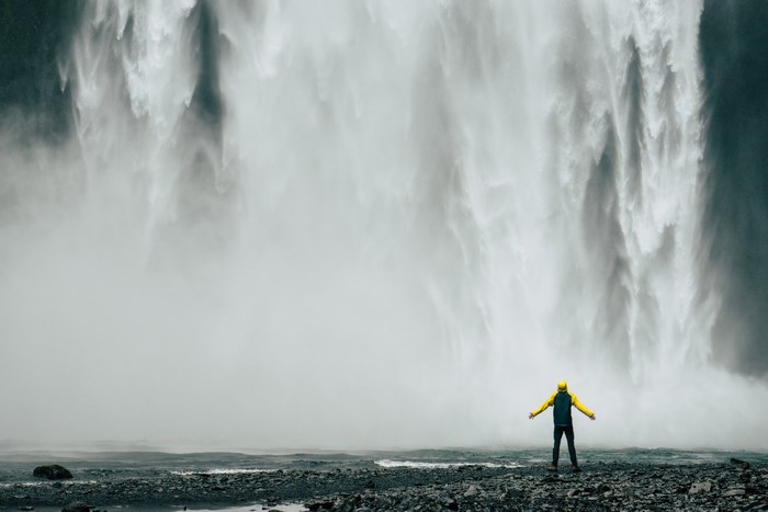 Person in yellow jacket at Skogafoss waterfall in Iceland