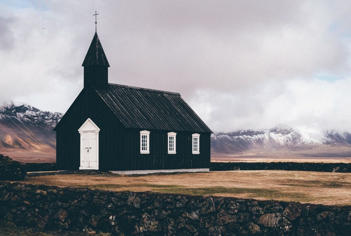 Black wooden church in Iceland with mountains