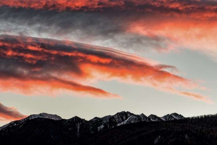 Dramatic sunset clouds over snow-capped mountains
