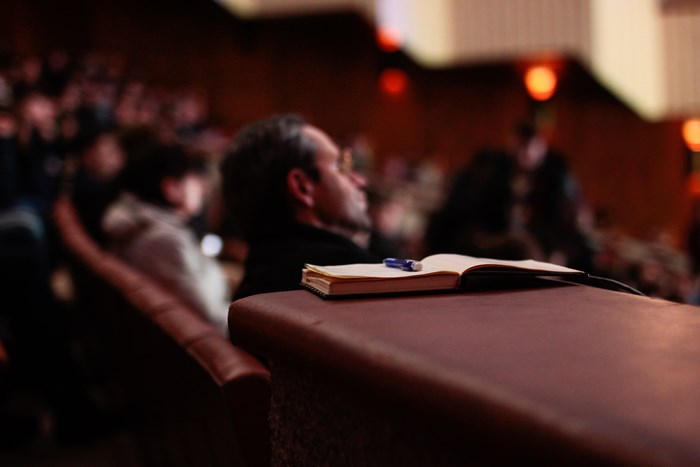 Man with notebook and pen in auditorium