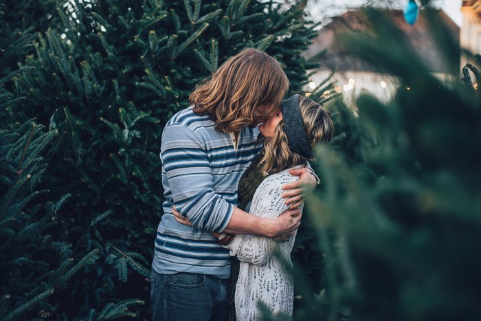 Couple kissing among Christmas trees