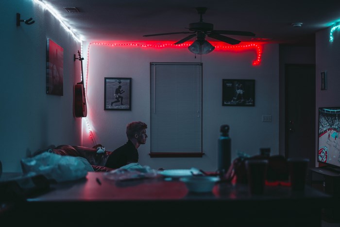 Man watching TV in a room with neon lights