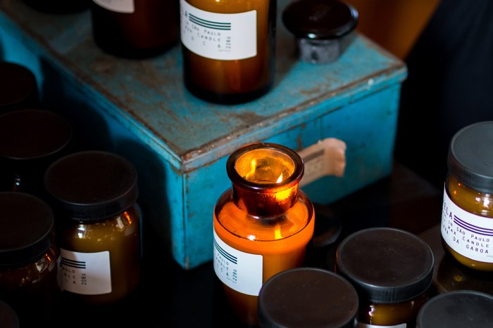 Burning candle in amber glass jar on blue metal box