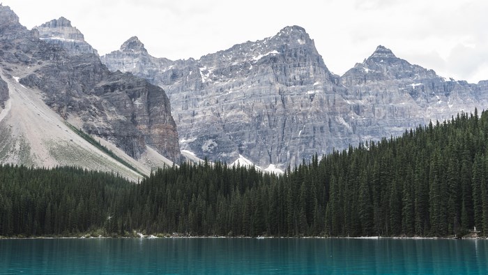 Turquoise lake and pine forest at the base of rugged mountains