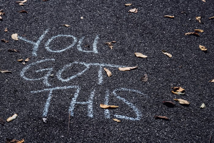 Chalk message 'You Got This' on asphalt with leaves