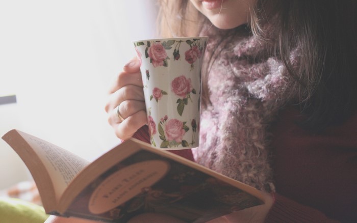 Girl reading a book and holding a floral mug