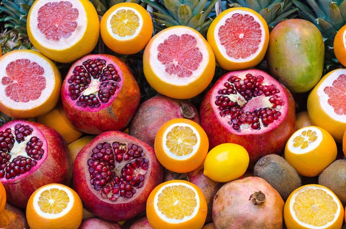 Assortment of colorful fruits including pomegranates, grapefruits, and oranges