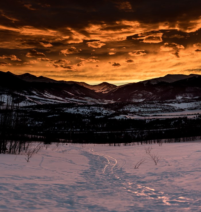 Snowy mountain range at sunrise with orange clouds