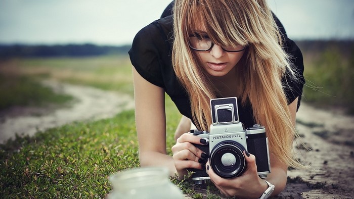 Woman with glasses holding a Pentacon camera