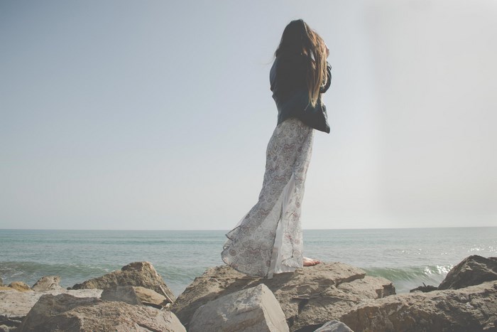 Woman in dress on rocks by the ocean