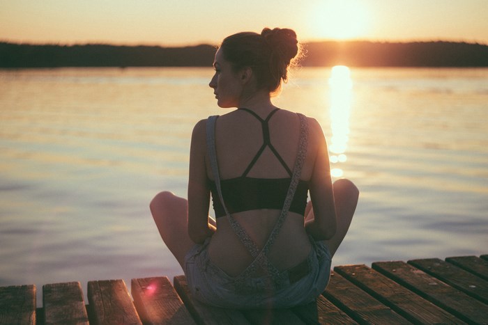 Woman sitting on a dock at sunset