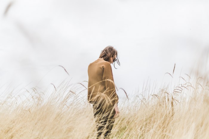 Woman in beige sweater walking in a grassy field