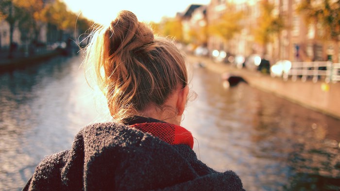 Woman with messy bun looking at a canal in the city