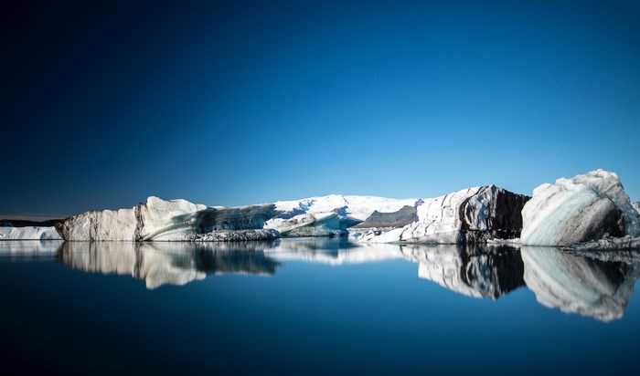 Icebergs reflecting in a calm ocean under a clear blue sky