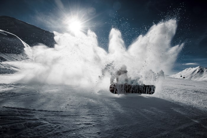 Snowboarder kicking up snow on a mountain slope