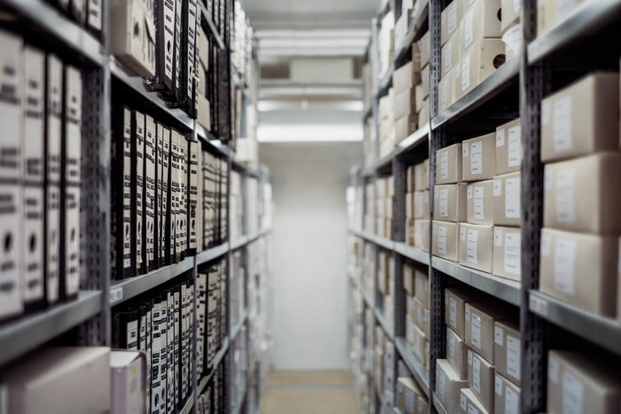 Rows of archive boxes and binders on shelves in a storage facility