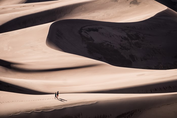 Couple Walking on Vast Desert Sand Dunes