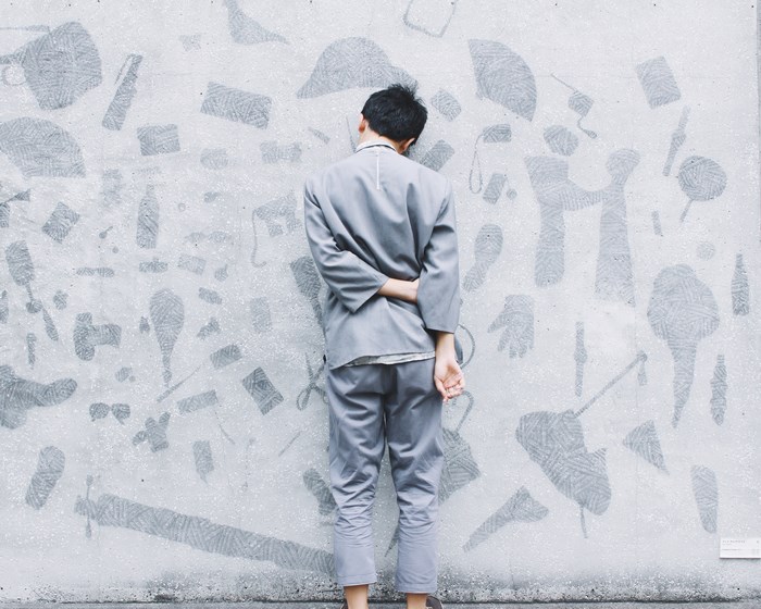 Person in grey suit looking at patterned wall