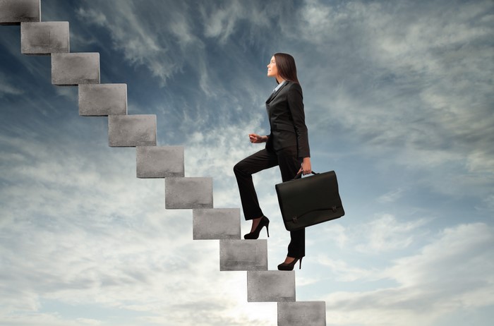 Woman in Suit Climbing Stairs in Sky