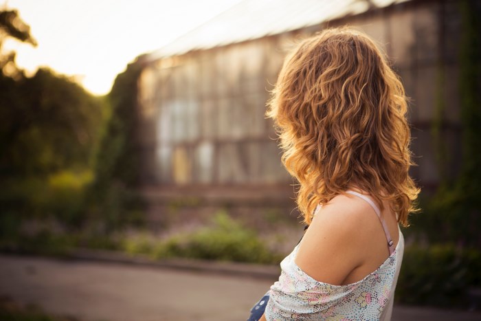 Woman with curly hair looking at a building at sunset