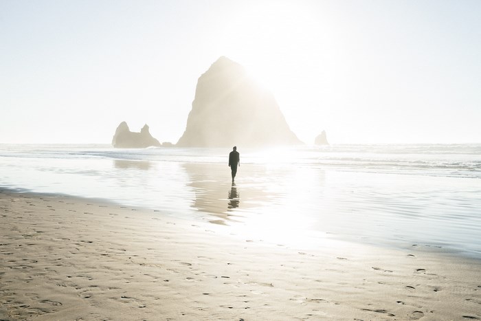 Man walking on Cannon Beach with Haystack Rock