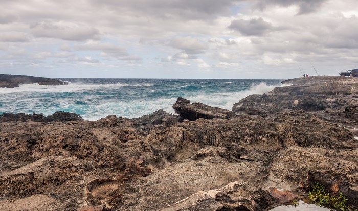 Rocky coast with crashing waves and fishermen in Hawaii