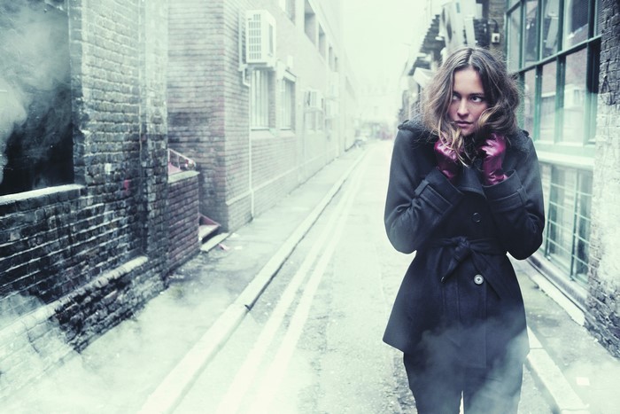 Woman in a dark coat in a foggy alley