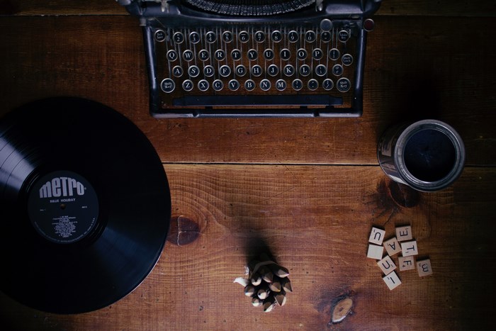 Typewriter, vinyl record, and scrabble tiles on a wooden table